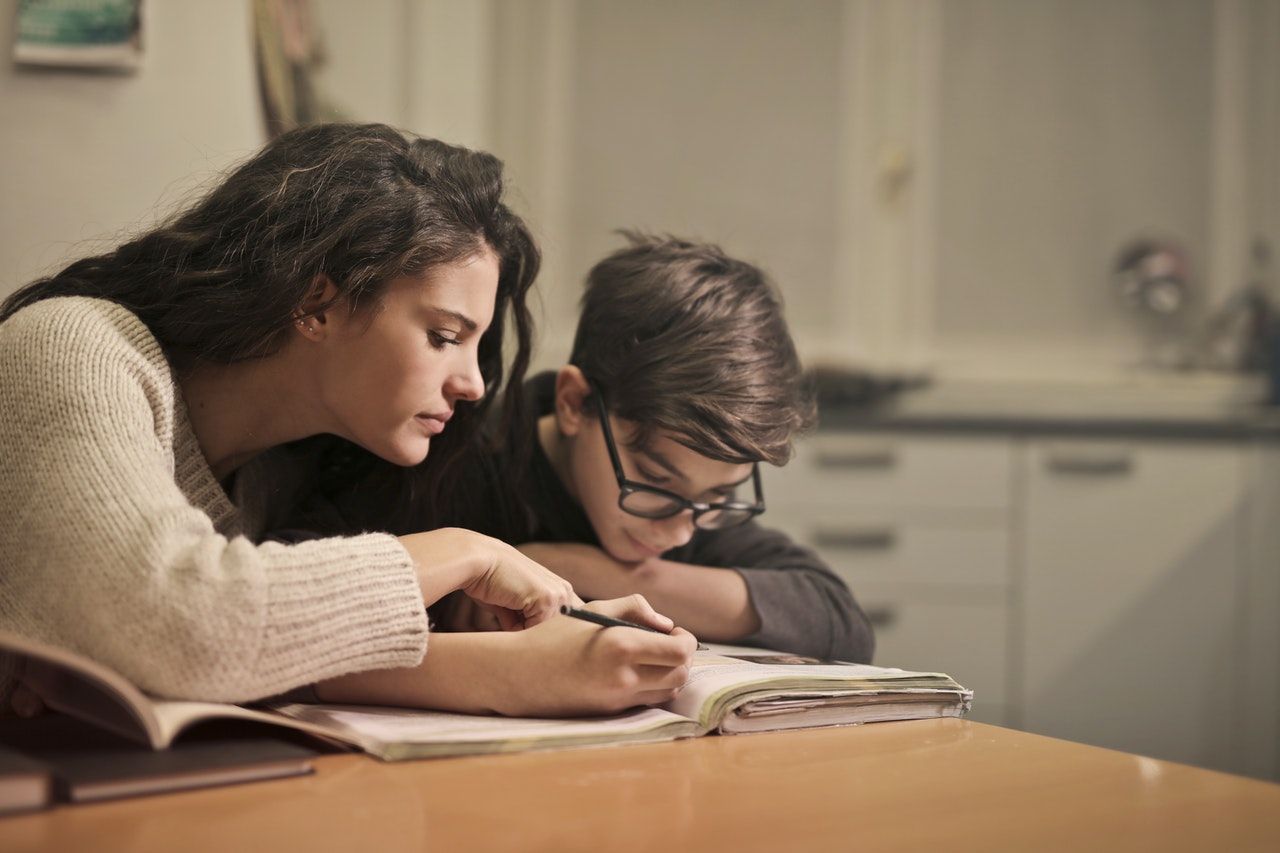 Frau hilft Jungen bei den Hausaufgaben
